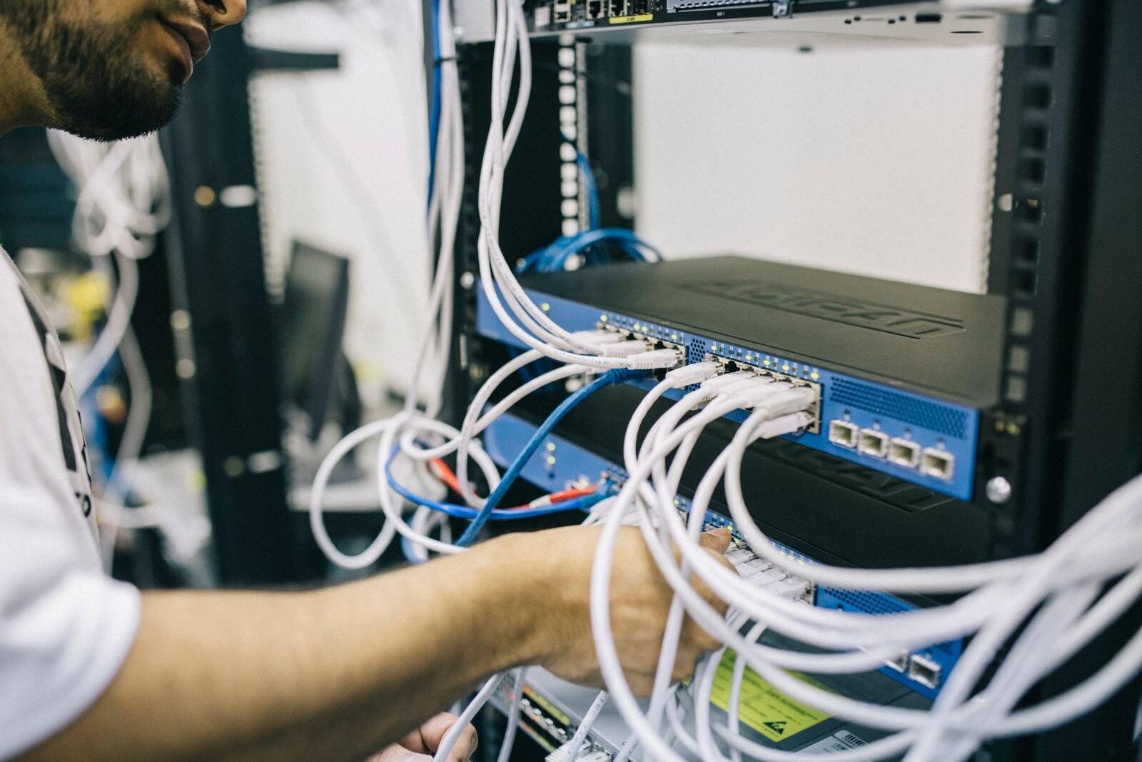 An engineer working on network cabling in a server rack.